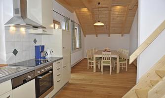 A modern kitchen with a wooden ceiling and a cozy dining table. The room is bright and pleasantly designed.