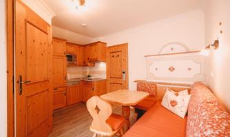 A cozy room with a wooden kitchen and a dining area. The walls are in warm tones, and the furniture creates an inviting atmosphere.