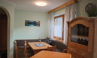 A cozy dining area with a wooden table and chairs. The walls are painted in soft colors, and the window brings in plenty of light to the room.