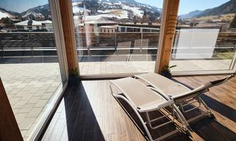 A bright room with large windows and a view of the mountains. Two loungers are on the wooden floor, inviting you to relax.