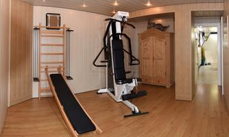A high-tech fitness room with several exercise machines. The room features bright wood decor and is well-lit.