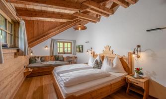 A cozy bedroom with wooden paneling and two beds. The room has large windows and an inviting atmosphere.