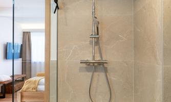 A modern shower with a glass partition and elegant tiles. The design is minimalist and bright.