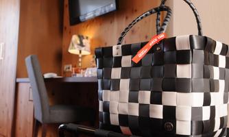 A stylish black and white handbag is placed on a chair in a modern room. In the background, a table, a chair, and a TV are visible.