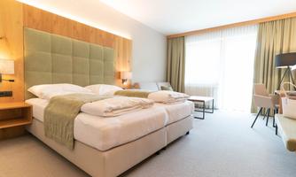 A modern hotel room with a large bed and luxurious decor. Bright colors and plenty of daylight create a relaxed atmosphere.