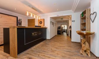 A modern reception area with a stylish wooden reception desk. The decor is bright and inviting, with a wooden shelf in the background.