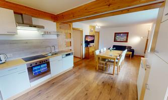 A modern kitchen with high-quality appliances and a large dining table. The space is bright and inviting, ideal for sociable meals.