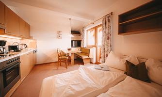 A cozy room with a double bed and a small dining area. The kitchen is modern and well-equipped.