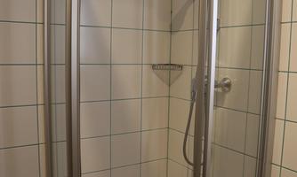 A modern shower cabin with glass walls and tiles. The space is bright and clean.