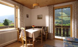A cozy living space with a dining area and a view of the mountains. Large windows let in plenty of light and create an inviting atmosphere.