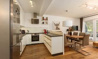 Modern kitchen with elegant furniture and hardwood flooring. Bright colors and plenty of light create an inviting atmosphere.