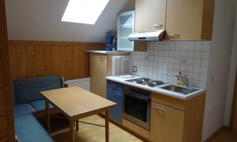 A small kitchen with a dining area and wooden paneling. The room has a skylight and modern kitchen elements.