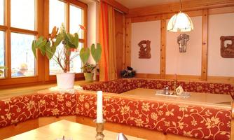 A cozy restaurant with wood-paneled walls and a red seating area. Large windows provide plenty of daylight and an inviting atmosphere.