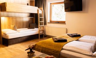 A cozy room with a double bed and a bunk bed. Large windows provide plenty of daylight.