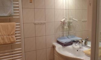 A modern bathroom with a bright tiled wall and a bathtub. Towels are neatly draped on a towel rack and a mirror illuminates the room.