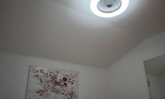 A modern room with an elegant ceiling lamp. A piece of art featuring red and gray colors hangs on the wall.