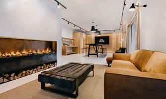 A stylish living space with a cozy sofa and a modern fireplace. The warm atmosphere is accentuated by wooden details and a clear design.
