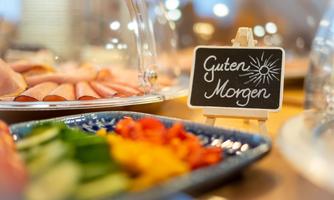 A buffet with fresh vegetables and various types of cold cuts. A sign reading "Good Morning" welcomes the guests.