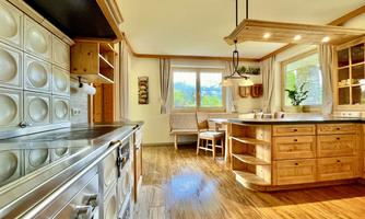 A modern, bright kitchen with wooden furniture and large windows. The space is friendly designed and offers plenty of room for cooking and relaxing.
