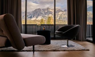 A modern living room with a view of majestic mountains. The large windows let in plenty of light and offer an impressive view.