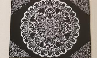 An artistic mandala in black and white. It features complex patterns and a symmetrical design.