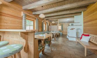 A cozy, paneled room with tables and benches. Large windows let in plenty of light and create an inviting atmosphere.