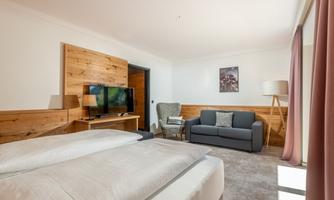 A modern room with a double bed and a television. Cozy seating and warm wood paneling create an inviting atmosphere.