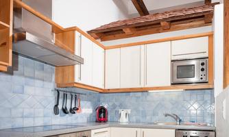 A modern kitchen with wooden shelves and blue tiles. The equipment includes a stove, a microwave, and various kitchen utensils.