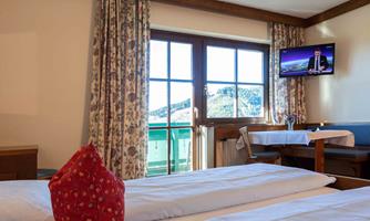 A cozy hotel room with two single beds and a television. Large windows offer a view outside, and the stylish decor creates an inviting atmosphere.