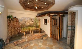 A cozy wellness area with a stone basin and rustic wood decor. The walls are decorated with a natural landscape motif.