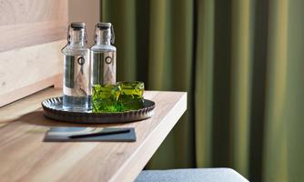 An elegant table with two water bottles and colorful glasses. In the background, green curtains are visible.