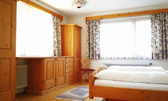 A cozy bedroom with wooden furniture. Large windows let in plenty of light.