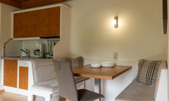 A cozy dining area with a wooden table and chairs. In the background, the kitchen is visible.