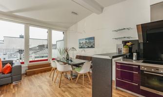 A modern apartment with an open living and dining area. Generous windows provide plenty of daylight and a bright atmosphere.