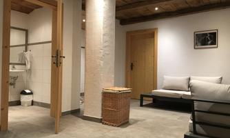 A modern room with a bright design and cozy furniture. On the left is a bathroom, and a laundry basket is in the room.