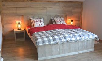 A cozy bedroom with a large wooden bed and red cushions. The soft lighting from lanterns creates an inviting atmosphere.