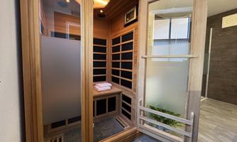 A modern wooden sauna with large windows. Towels are ready on a bench.