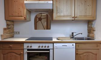 A modern kitchen with wooden cabinets and white appliances. The kitchen includes a stove, a sink, and a dishwasher.