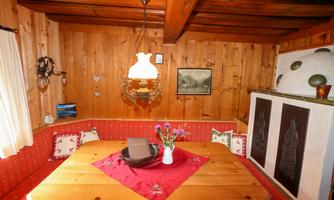 A cozy room with wooden walls and a large wooden bench. The table is decorated with a red tablecloth and a vase of flowers.