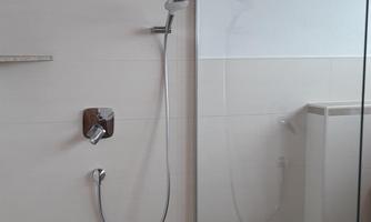 A modern shower with transparent glass doors and a bright tile design. The room feels clean and minimalist.