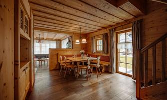 A cozy dining area in a wooden house. The room is bright and inviting, with a large table and chairs.