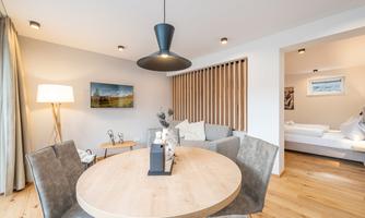 A modern living room with a round wooden table and comfortable chairs. The rooms are bright and well-designed, with a cozy atmosphere.