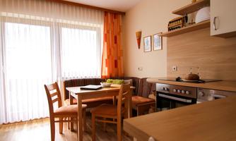 A modern kitchen with a table and chairs.  
Large windows let in plenty of light and create a bright atmosphere.