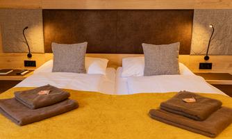A cozy bedroom with two beds and soft pillows. The decoration is modern and inviting, with yellow and gray hues.
