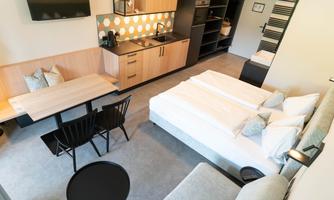 A modern room with a double bed, a dining table and chairs. The kitchen is well-equipped and there is a cozy living area.
