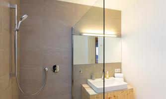 A modern bathroom with a glass shower and a wooden sink. The walls are in neutral colors, conveying a calm impression.
