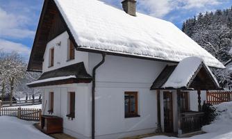 A charming house in the snow with a snow-covered roof. Surrounded by a wintry landscape and trees.