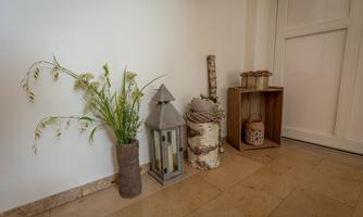 A cozy entrance area with decorative elements.  
Vases, lanterns, and wooden objects create an inviting atmosphere.