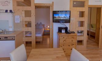 A bright apartment with wooden furniture and a cozy atmosphere. In the background, bedrooms and a television are visible.