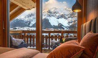 A cozy bedroom with a view of snow-covered mountains. A beautiful winter landscape can be seen through the window.